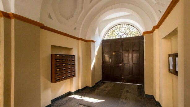 A hallway with a wooden door, a wall-mounted safe, and a stained glass window. - GuestHost - Studio apartment 5 minutes from the Mole and Royal Gardens! (Torino)