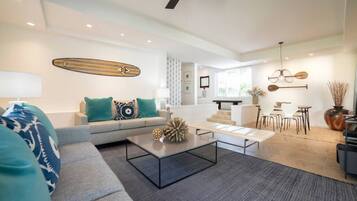 A modern living room with a sofa, coffee table, and dining area.