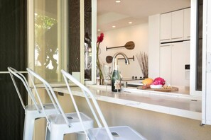 A modern kitchen with white cabinets, a stainless steel faucet, and a countertop with a bottle of champagne.