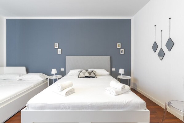 A hotel room with a large bed, two bedside tables, a headboard, and a wall-mounted light fixture.