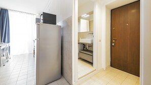 A kitchen with a refrigerator, a sink, and a wooden door.