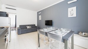 A modern kitchen with a dining area, grey walls, and a flat-screen TV mounted above the table.