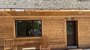 A wooden cabin with a large window, a door, and two rocking chairs and a small table outside. - Adults 25 plus Only, Creekside Vacation Rental 1, Downtown Historic CITY APPROVE (Buffalo)