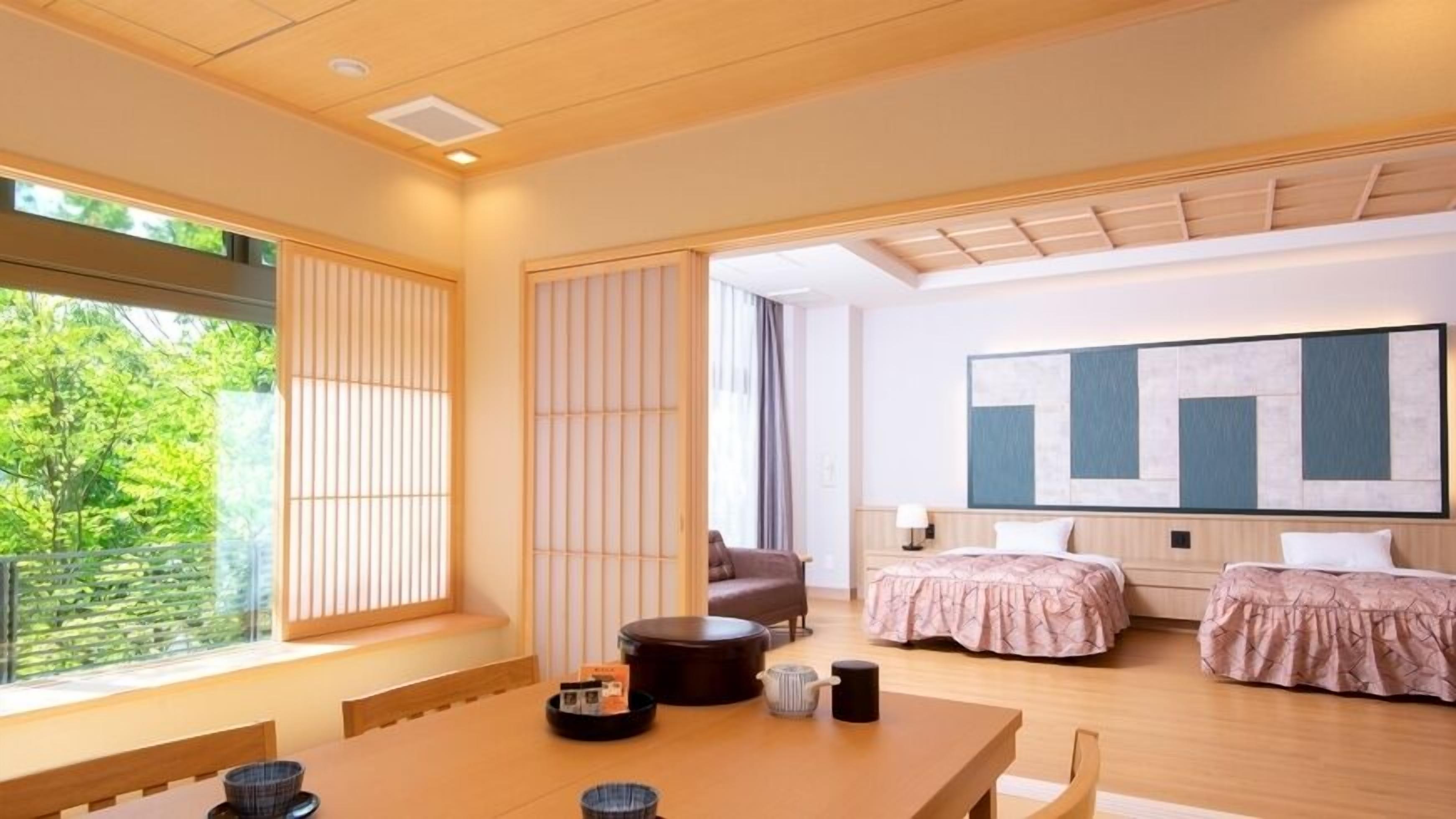 A modern hotel room with a large window, a dining area, two beds, and a large abstract painting on the wall.