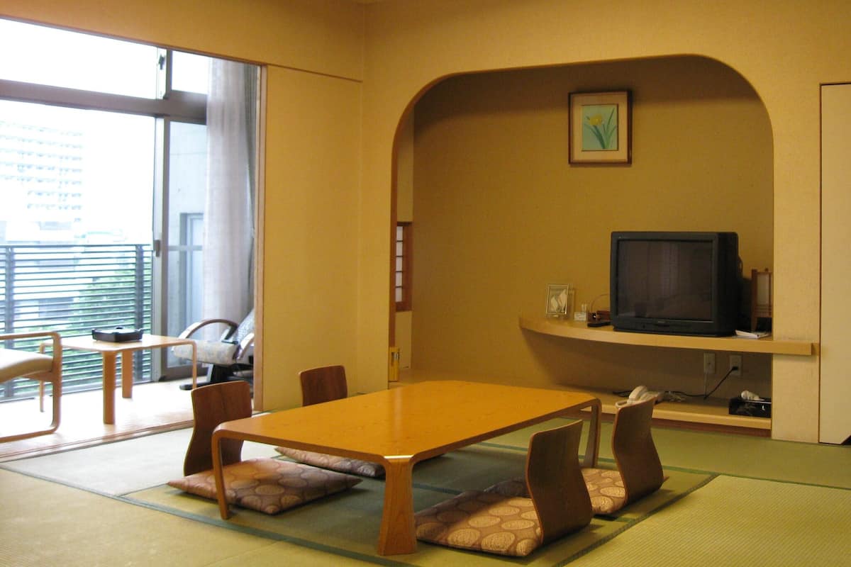 A room with a wooden table, chairs, a television, and a picture on the wall.