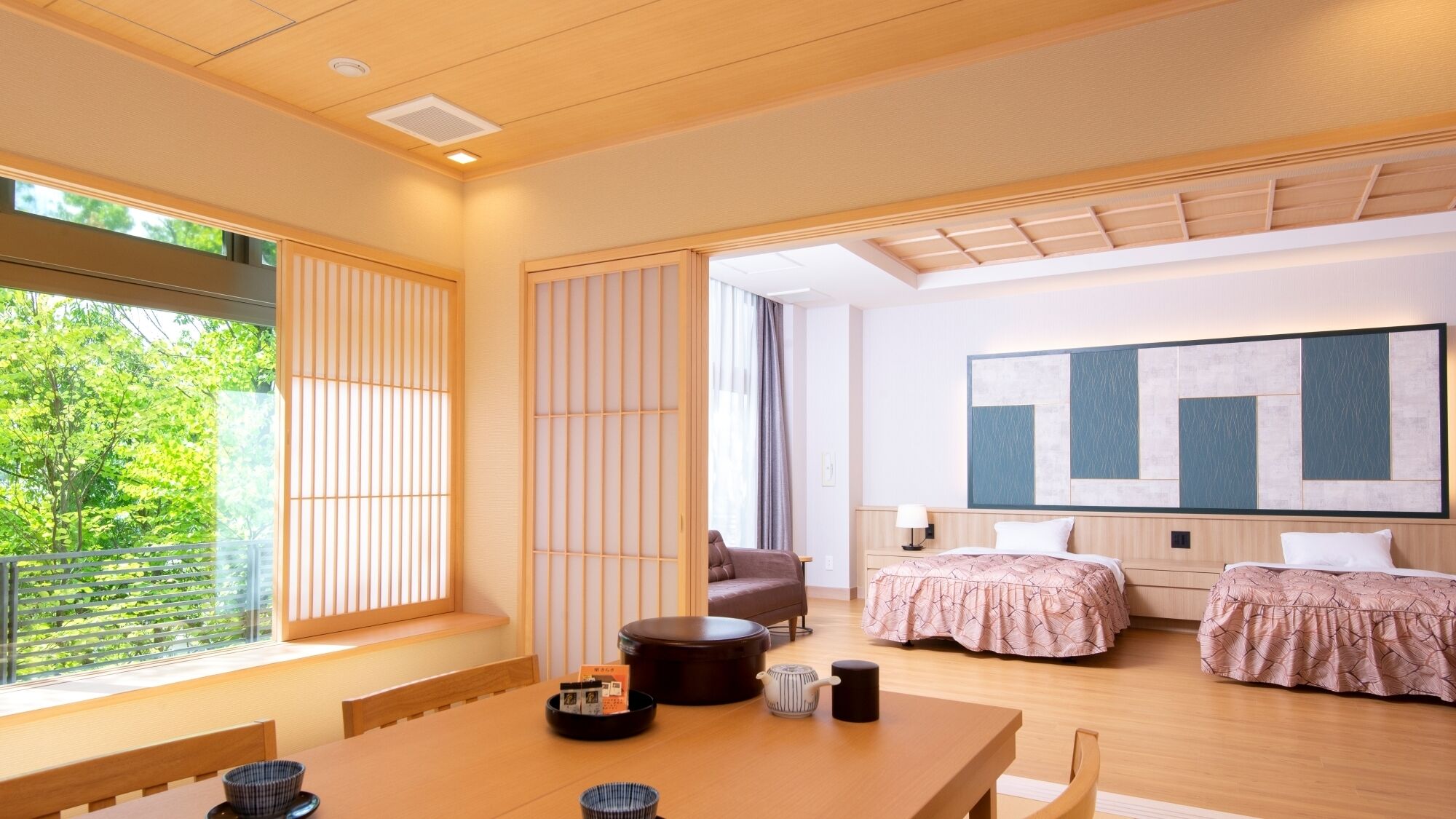 A modern hotel room with a large window, a dining area, two beds, a sofa, and a large abstract painting on the wall.