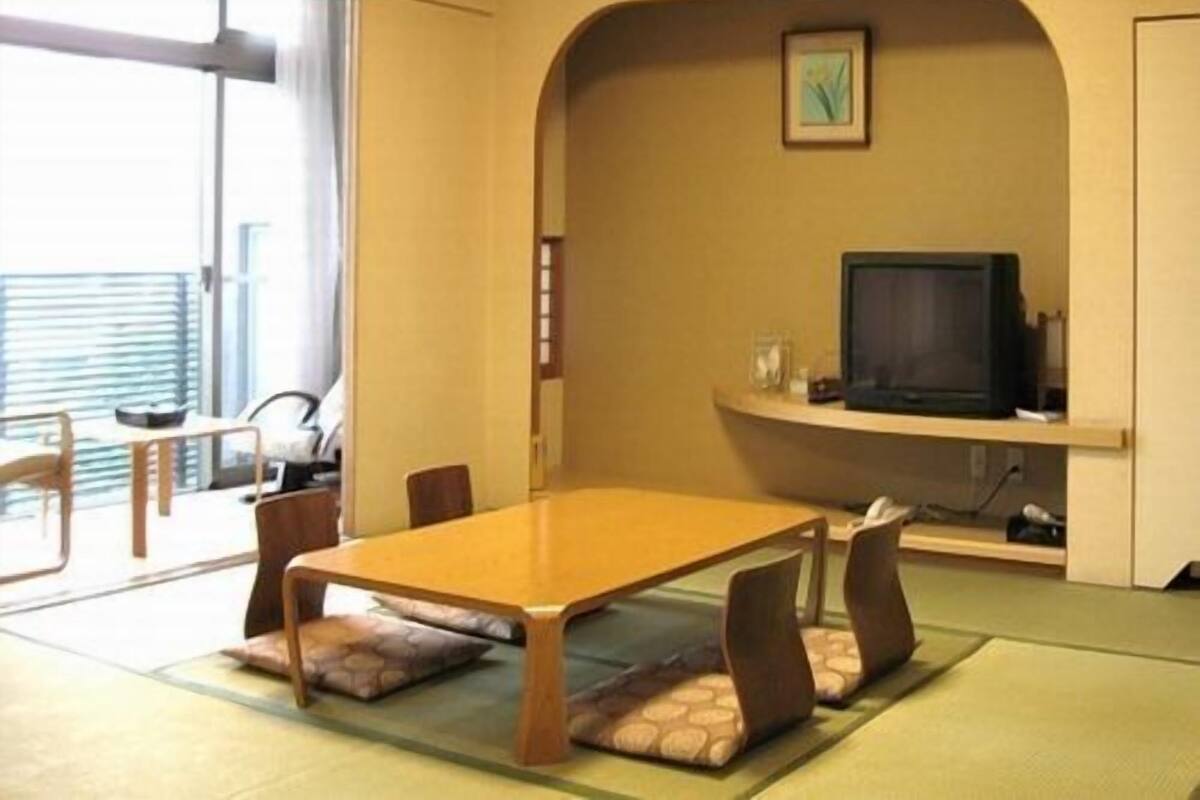 A conference room with a table, chairs, a television, and a picture on the wall.
