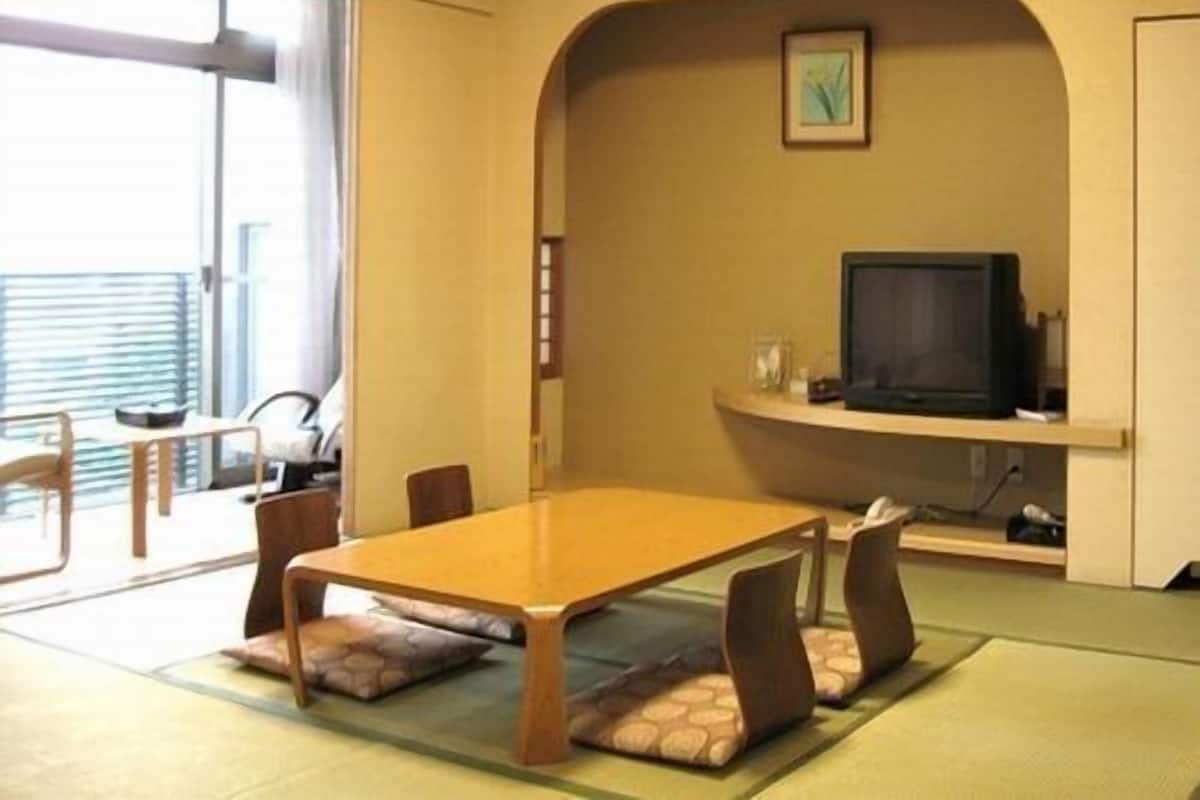 A conference room with a table, chairs, a television, and a picture on the wall.