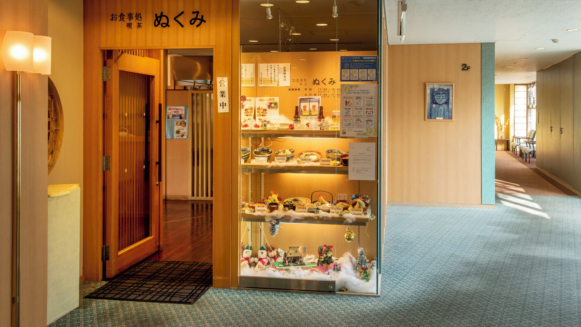 A traditional Japanese restaurant with a wooden interior, a display of dishes, and a Christmas decoration.