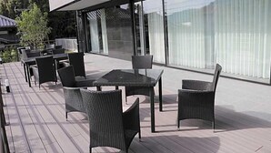 An outdoor patio area with tables and chairs, large windows, and a view of the surrounding landscape. - Yado Hanasaku (Tateyama)