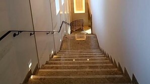 Una escalera con barandilla que conduce a un rellano con una lámpara.