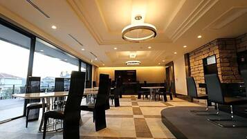 Um lobby de hotel moderno com piso xadrez, parede de detalhes em pedra e uma grande janela com vista.