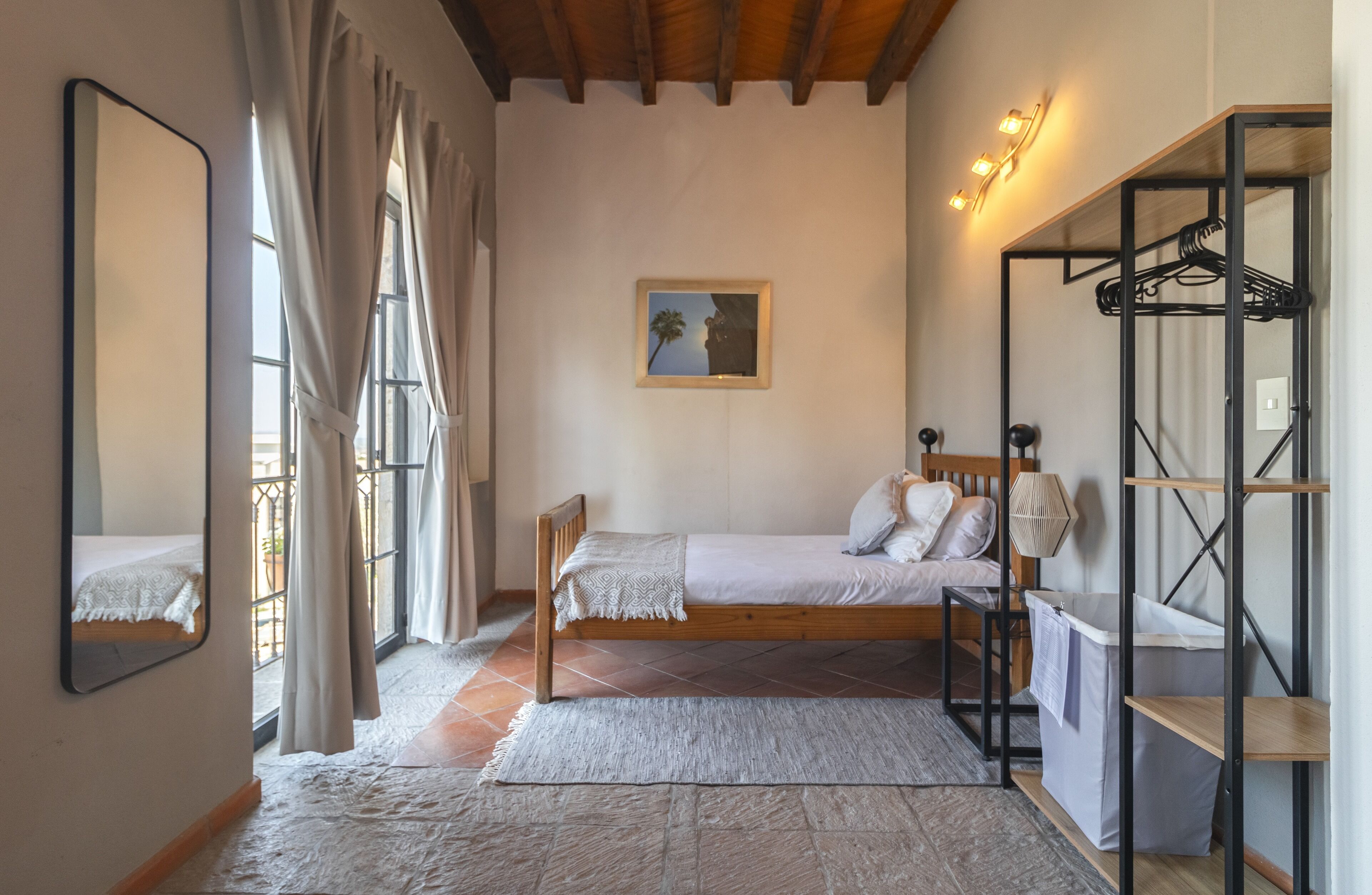 A bedroom with a wooden bed, a mirror, a painting, and a wardrobe.