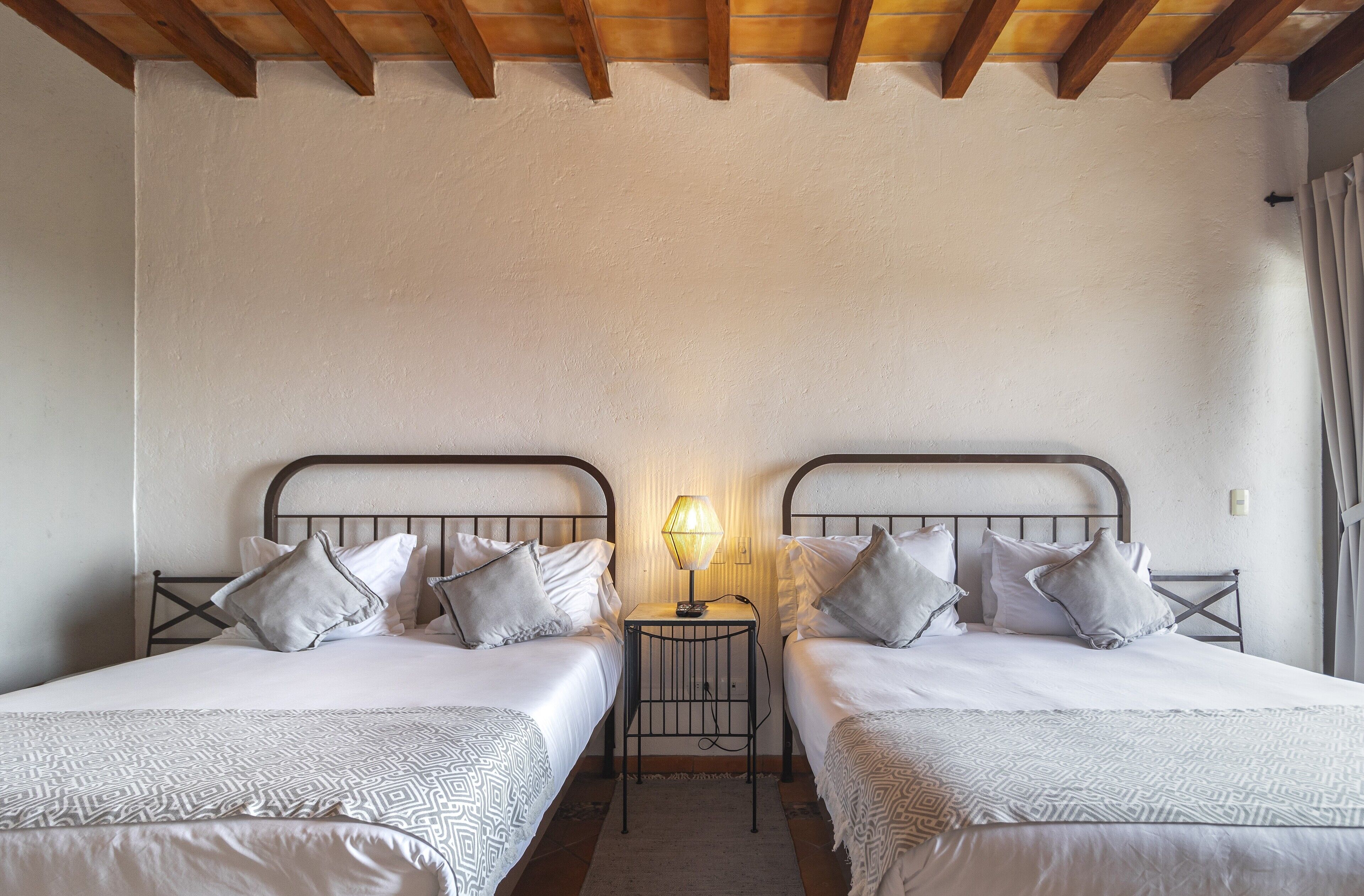 Une chambre avec deux lits, une table de chevet avec une lampe et un plafond en bois.