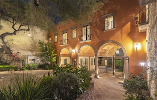 A courtyard with arched walkways, stone walls, and potted plants.