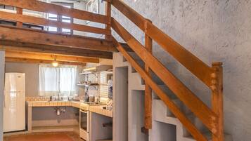 Una cocina rústica con una escalera de madera, un farol rojo y suelo de baldosas.