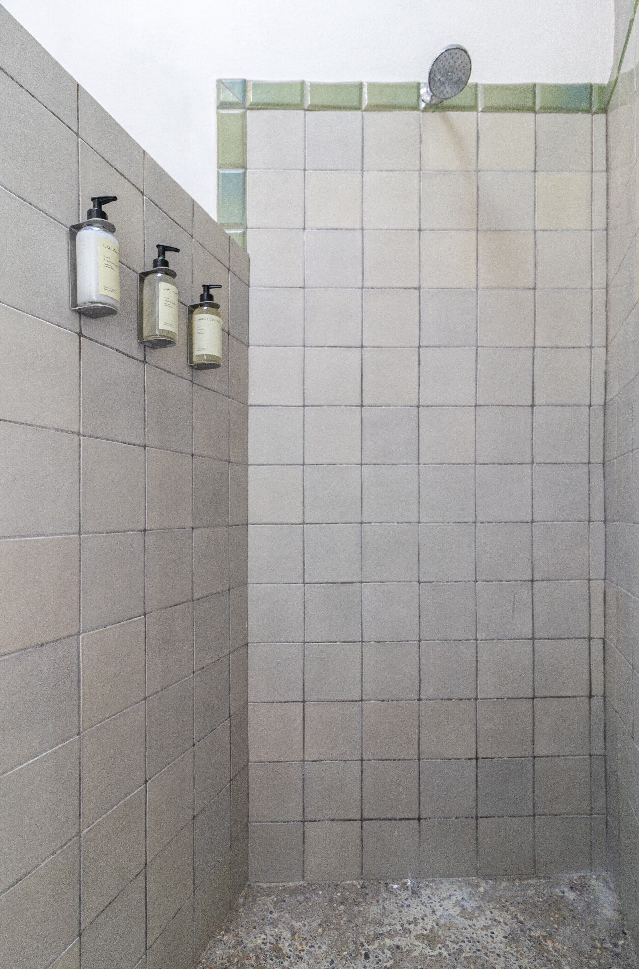 Un espacio de ducha con paredes de azulejos y un cabezal.