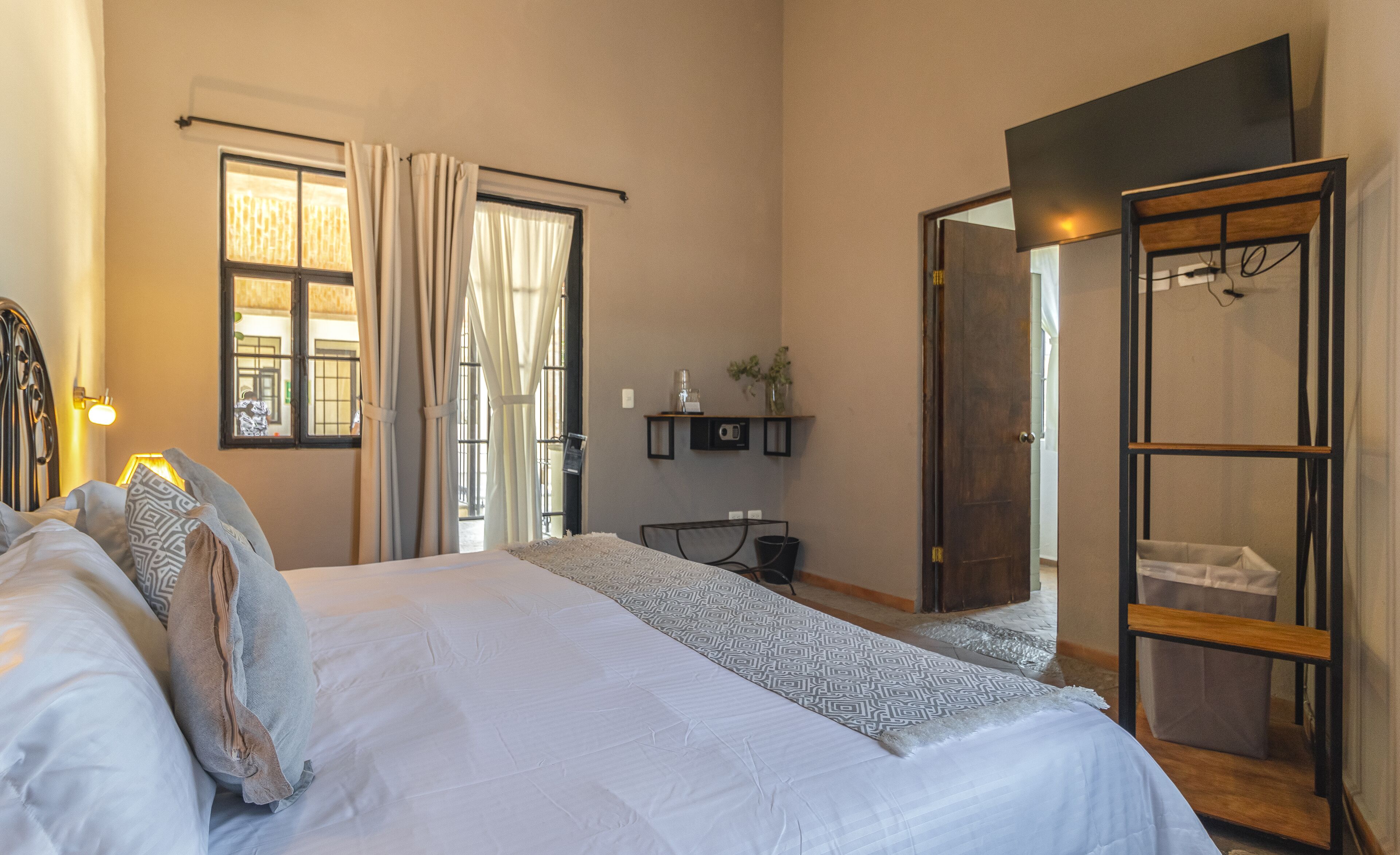 A bedroom with a large bed, a bedside table, a mirror, and a wardrobe.