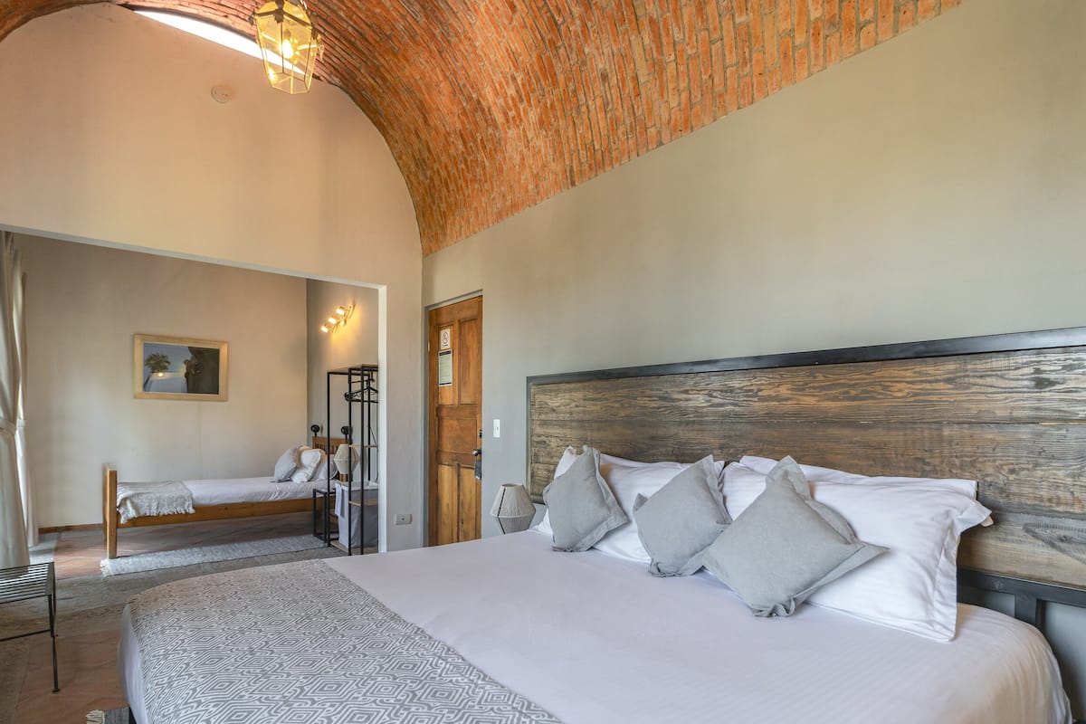 A bedroom with a large bed, a wooden headboard, and a mirror.