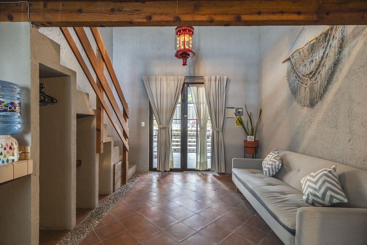 A hallway with a sofa, a water dispenser, a staircase, and a red lantern.