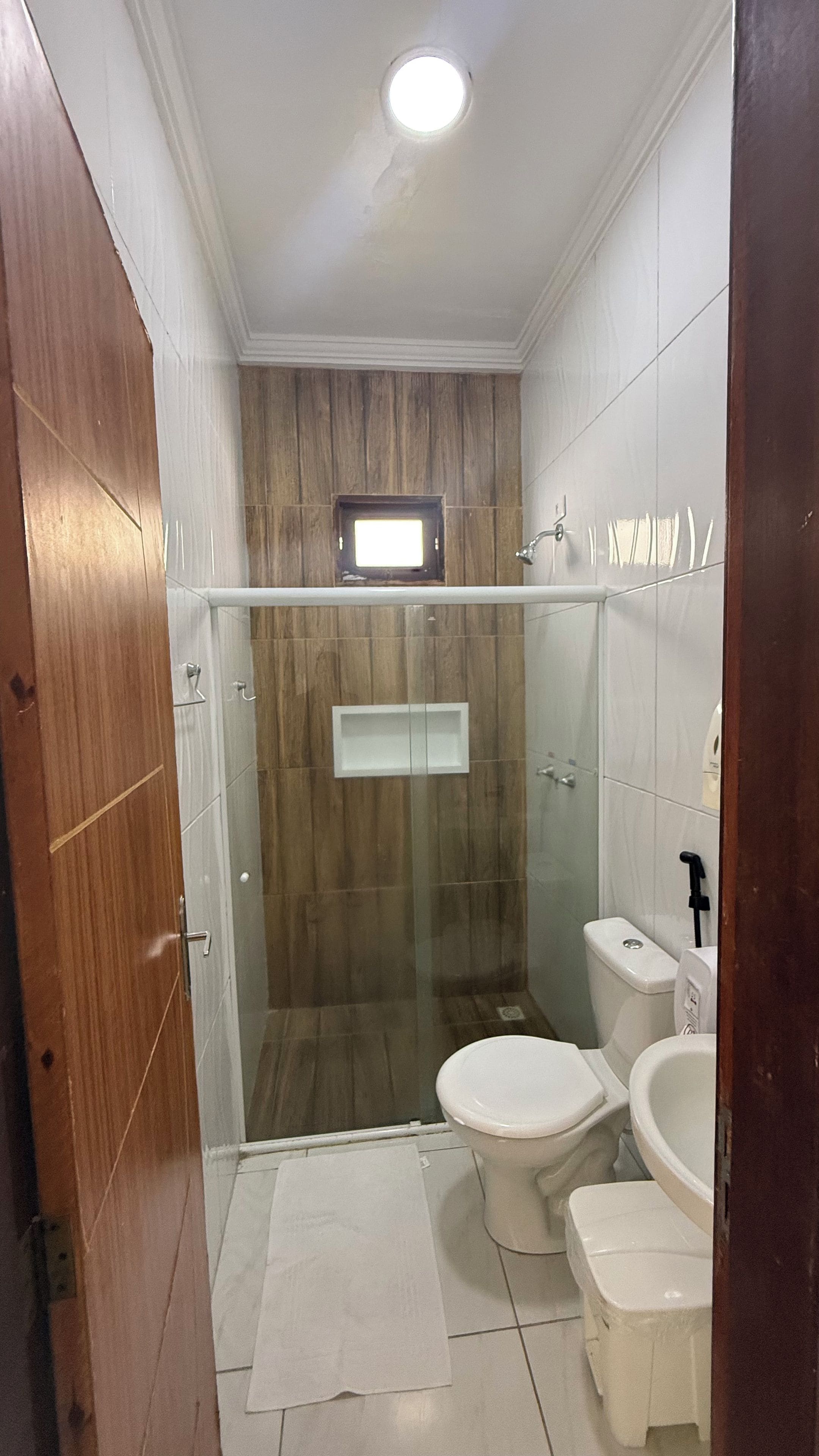 Casa de banho com chuveiro separado por vidro, sanita, bidé e lavatório.