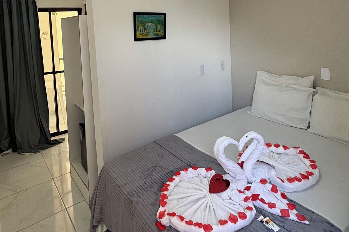 Ein Hotelzimmer mit Bett, Klimaanlage, einem Gemälde und Blick ins Freie.
