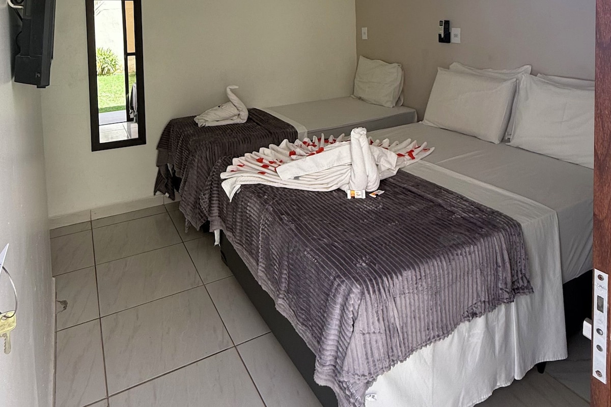 Ein Hotelzimmer mit zwei Betten, einem flachbildfernseher an der Wand und einem kleinen Fenster.