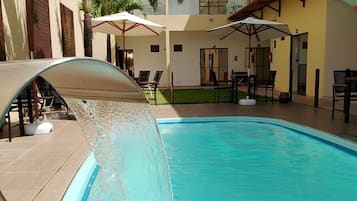 Una piscina al aire libre, sillones reclinables de piscina