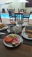 Una mesa de comedor con platos de comida, una taza de café y un tazón de cereal.