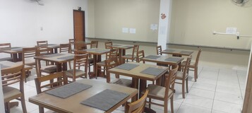 Un aula con mesas y sillas de madera, una pizarra y una puerta.