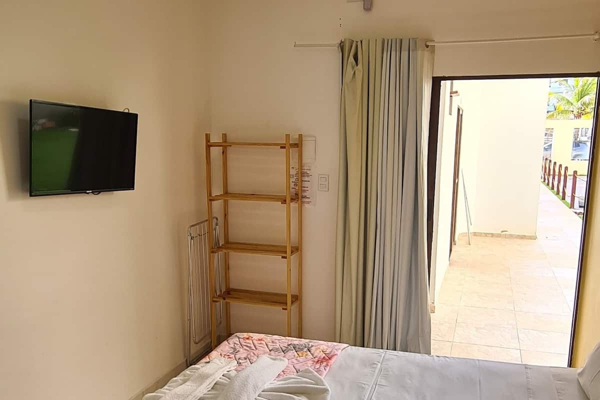 Ein Schlafzimmer mit Bett, Fernseher, einer Holzkammer und Blick ins Freie.