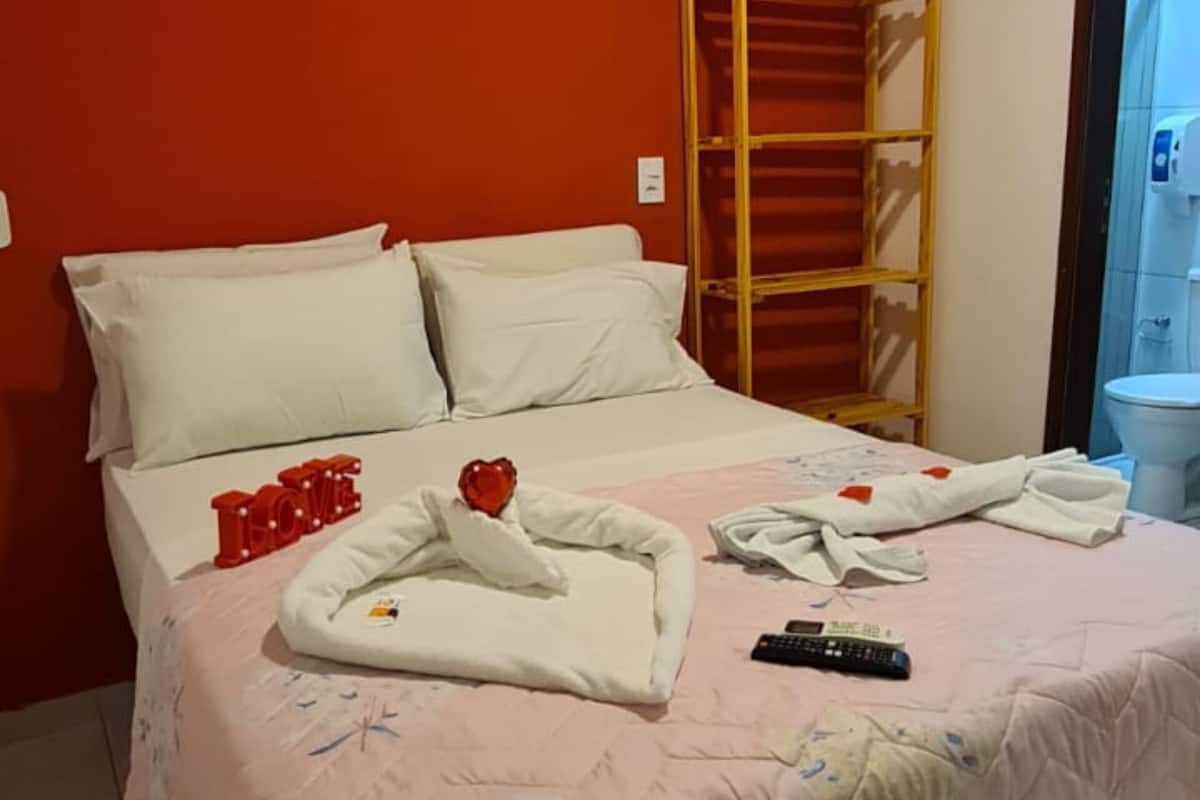 Ein Hotelzimmer mit einem Bett, einer Holzleiter, einer Klimaanlage und einem durchgegangenen Tür erkennbaren Badezimmer.
