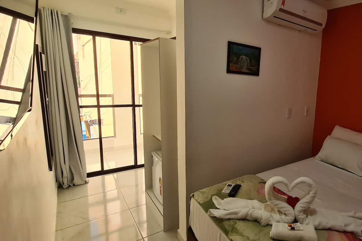Ein Hotelzimmer mit Bett, einem Bild an der Wand und Blick aus dem Fenster.