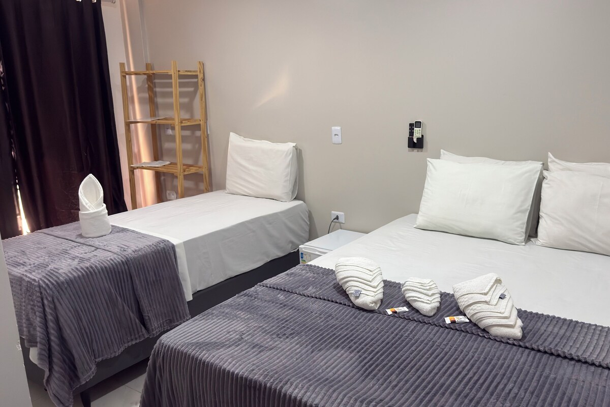 A hotel room with two beds, a wooden ladder, a white pillow, and a towel on the floor.