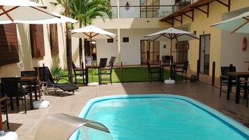 Una piscina al aire libre, sillones reclinables de piscina