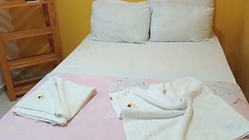 Uma cama de solteiro com roupa de cama e almofadas brancas, uma escada de madeira e um edredom rosa com estampas florais.