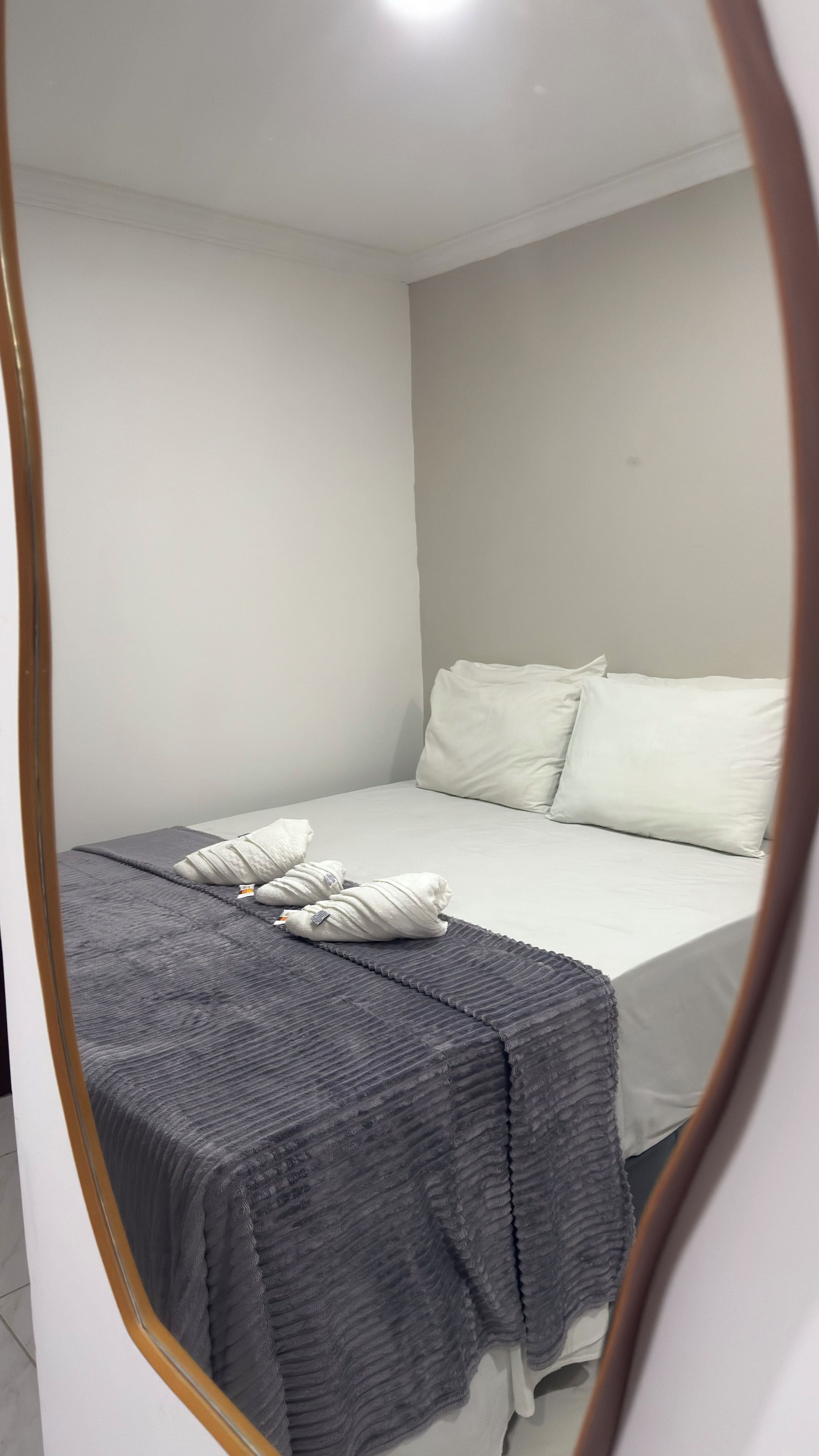 A bedroom with a bed, pillows, and a blanket.