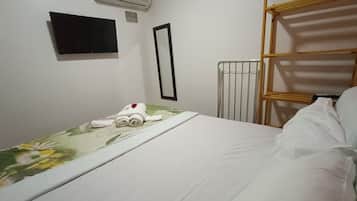 Quarto de hotel com cama, televisão na parede, ar condicionado e radiador.