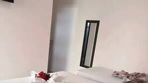 Een hotelkamer met twee bedden, elk voorzien van keurig opgevouwen witte handdoeken en een boeket rode rozen op een van de bedden.