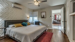 Un dormitorio con una cama, ventilador de techo y ventana.