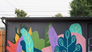 Un mural de plantas coloridas y un pájaro en una pared de edificio.