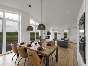 A modern dining area with a wooden table, leather chairs, and pendant lighting.
