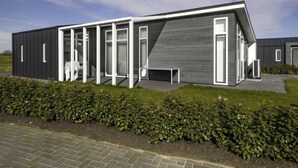 Ein modernes Gebäude mit flachem Dach, großen Fenstern und einem gepflasterten Eingang.