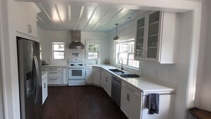 Une cuisine avec des armoires blanches, un réfrigérateur en acier inoxydable, une cuisinière et un évier.
