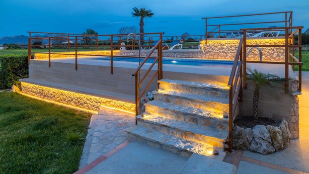 Eine Steintreppe führt zu einem Poolbereich mit Blick auf die Landschaft.