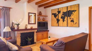 Ein Wohnzimmer mit Kamin, Sofas, einem Couchtisch, einem Fernseher und einer Weltkarte als Wandbild.