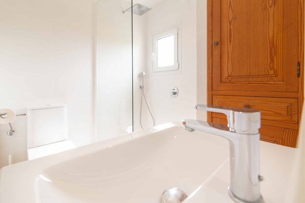 Un baño con una bañera blanca, cabina de ducha de vidrio, puerta de madera y un inodoro.