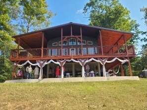 Stunning two-story building with a central entrance and balcony overlooking a serene natural setting.