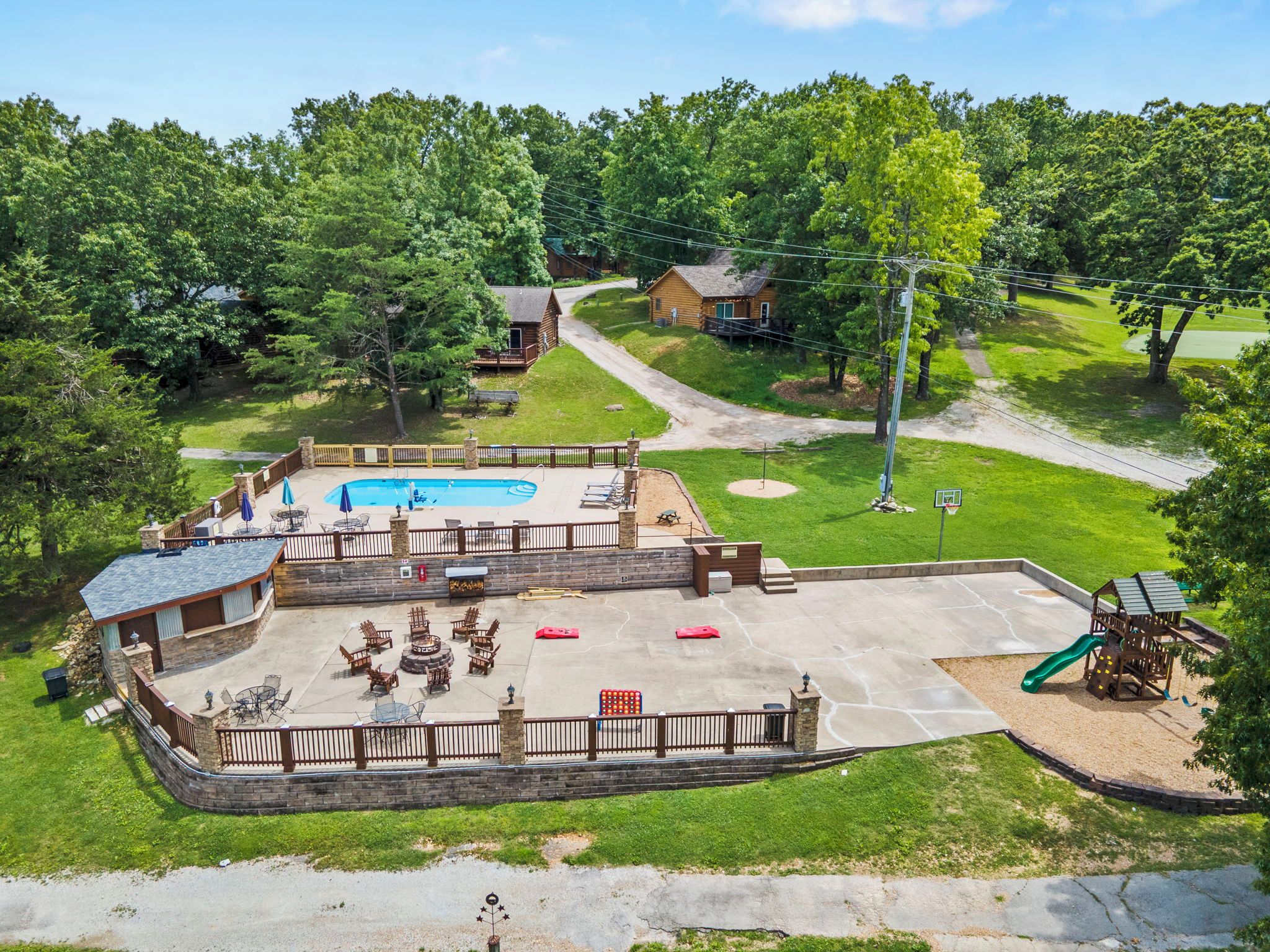 A residential backyard with a swimming pool, patio furniture, and a children's play area.