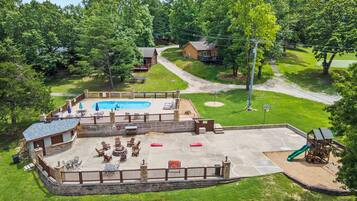 A residential backyard with a swimming pool, patio furniture, and a children's play area.